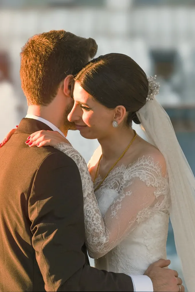 Düğün gününde sarılan gelin ve damat, dantel gelinlik ve tül duvak